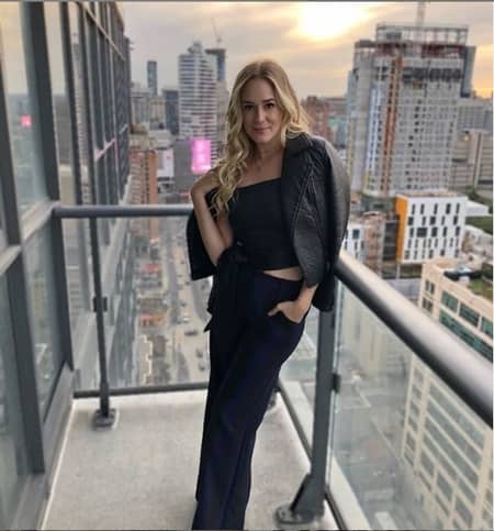 Brittany Bristow standing on the balcony of her friend's apartment in Canada with a beautiful backdrop